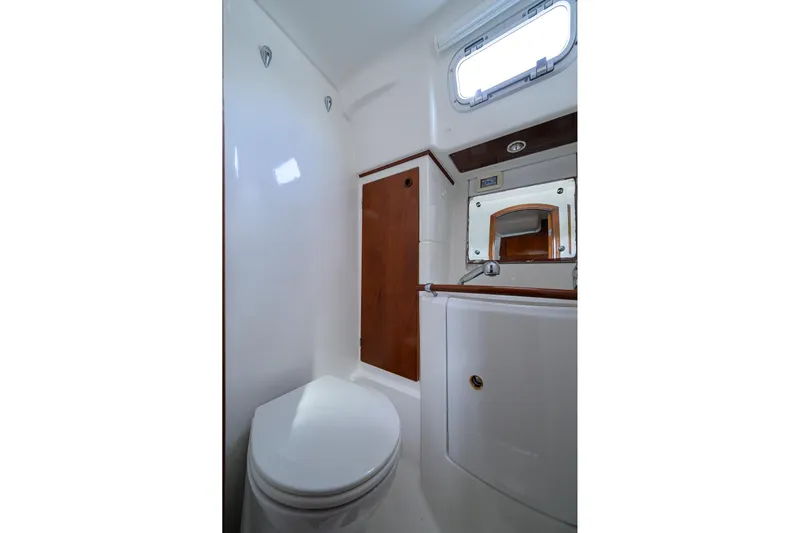 Windigo Yacht Photos Pics Bathroom interior of 2003 Beneteau 50 yacht, featuring toilet, mirror, and wooden accents.