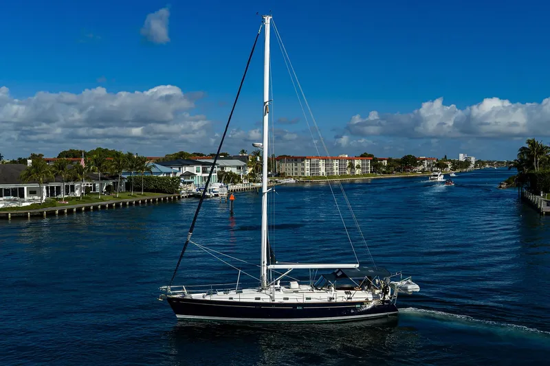 Windigo Yacht Photos Pics Sailing yacht Beneteau 50 (2003) cruising on a scenic waterway under a clear blue sky.