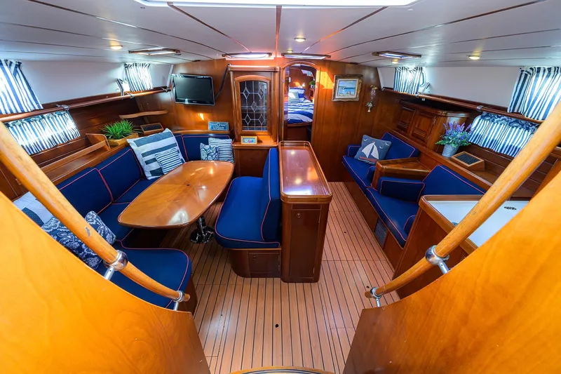 Windigo Yacht Photos Pics Luxurious interior of a 2003 Beneteau 50 yacht with elegant wood finish and blue seating.