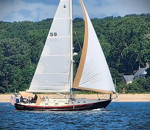 Indigo Yacht Photos Pics Sailboat Pacific Seacraft 40, 2005 model, sailing near a forested shoreline.