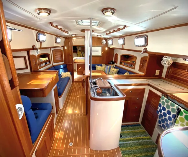 Indigo Yacht Photos Pics Luxurious interior of a 2005 Pacific Seacraft 40 sailboat with wood finishes and blue seating.