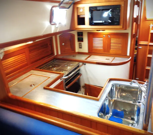Indigo Yacht Photos Pics Interior of 2005 Pacific Seacraft 40 yacht kitchen with wood cabinetry and stainless steel sink.