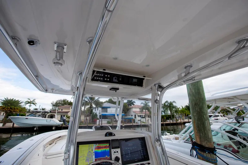 Bandit Yacht Photos Pics 2018 Jupiter 38 FS boat console with navigation screens and controls, docked near waterfront homes.