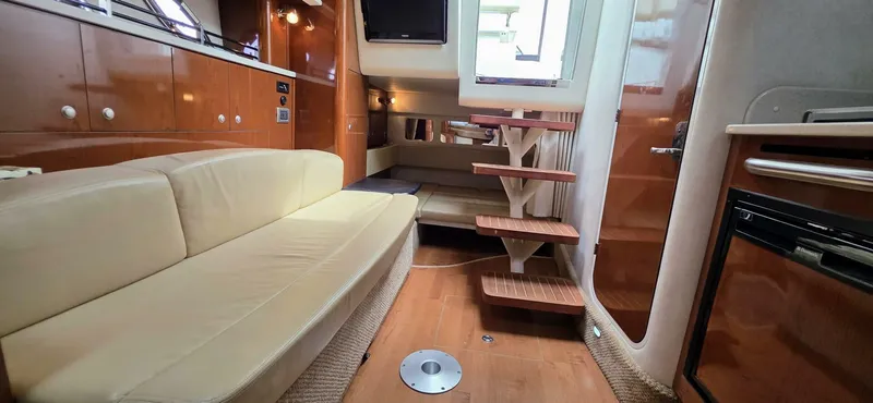  Yacht Photos Pics Interior of 2009 Sea Ray 310 Sundancer, featuring beige seating, wooden cabinetry, and compact kitchen area.