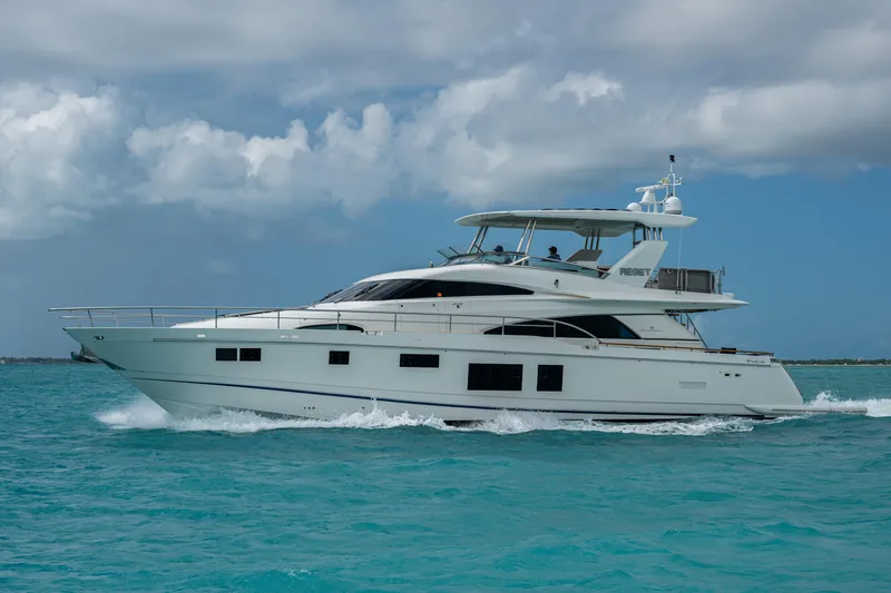 Reset Yacht Photos Pics Luxury 2015 Fairline 78 Squadron yacht cruising on turquoise waters under a cloudy sky.
