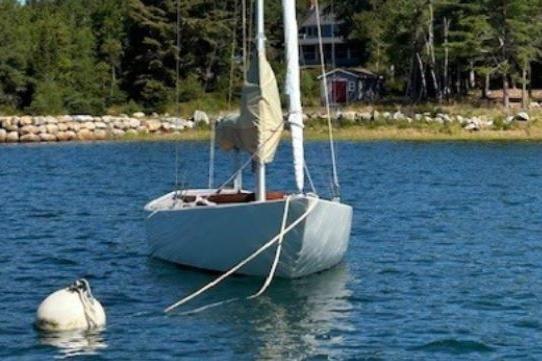 Sailboat Rustler 24 (2010) moored on a serene lake with forested shoreline.