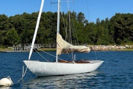 Sailboat Rustler 24, 2010 model, anchored on a serene lake with forest backdrop.