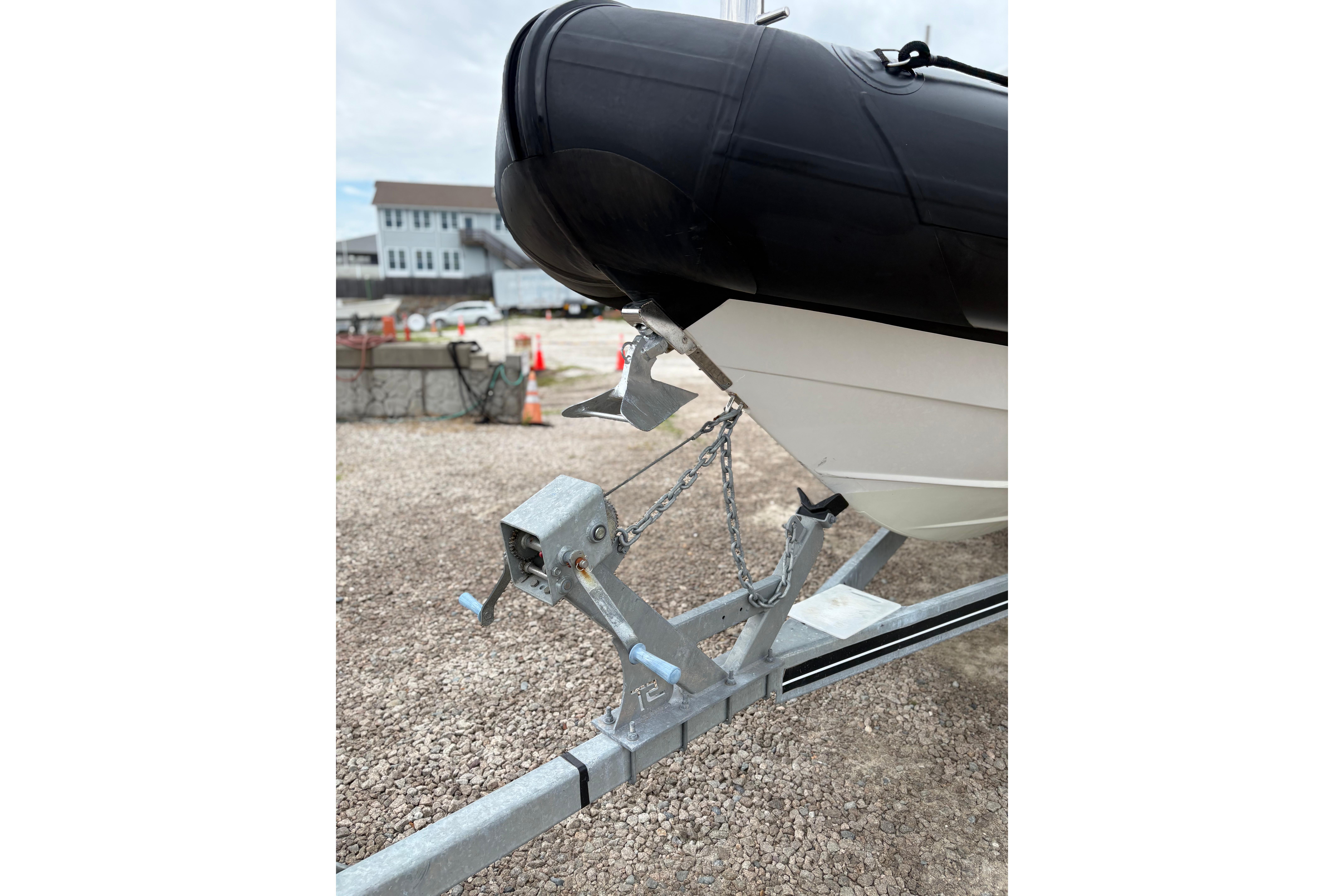 2020 Protector 310 Targa boat on trailer, secured with chains, in a gravel lot.