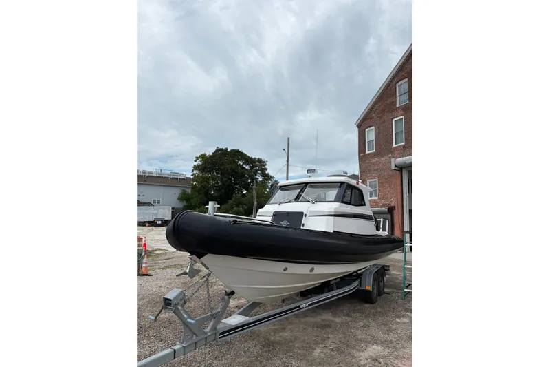 Protector Yacht Photos Pics 2020 Protector 310 Targa boat on trailer, parked near brick building under cloudy sky.