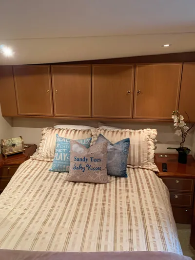  Yacht Photos Pics Cozy bedroom in 2004 Ocean Yachts 57 Odyssey with nautical-themed pillows and wooden cabinets.