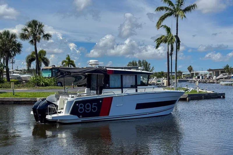  Yacht Photos Pics 2018 Jeanneau NC 895 boat docked by palm trees under a blue sky.