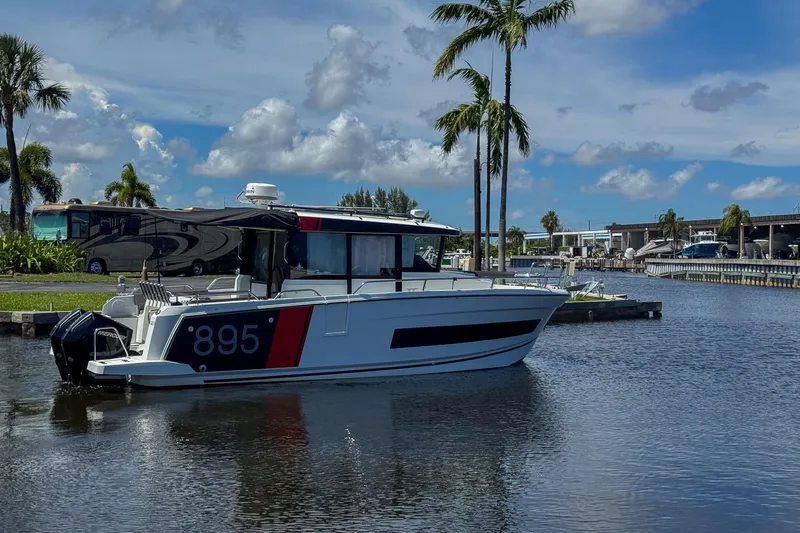  Yacht Photos Pics 2018 Jeanneau NC 895 boat docked on a sunny day with palm trees and blue sky.