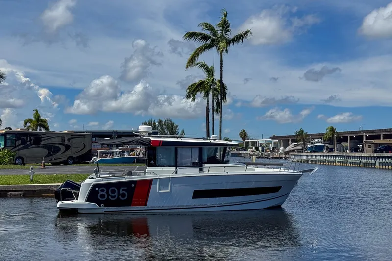  Yacht Photos Pics 2018 Jeanneau NC 895 boat docked on a sunny day with palm trees in the background.