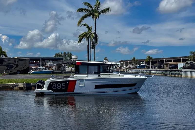  Yacht Photos Pics 2018 Jeanneau NC 895 boat docked on a sunny day with palm trees in the background.