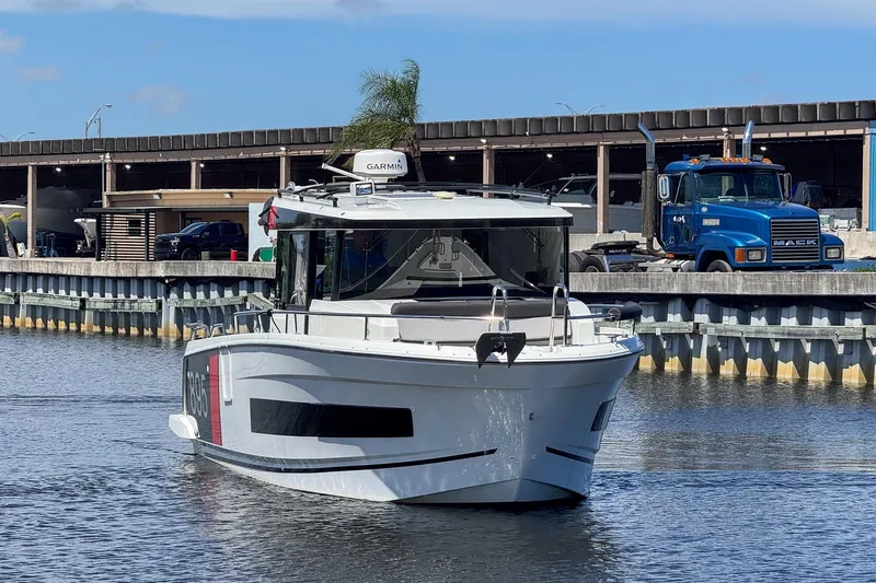  Yacht Photos Pics 2018 Jeanneau NC 895 boat on water near industrial area with truck in background.