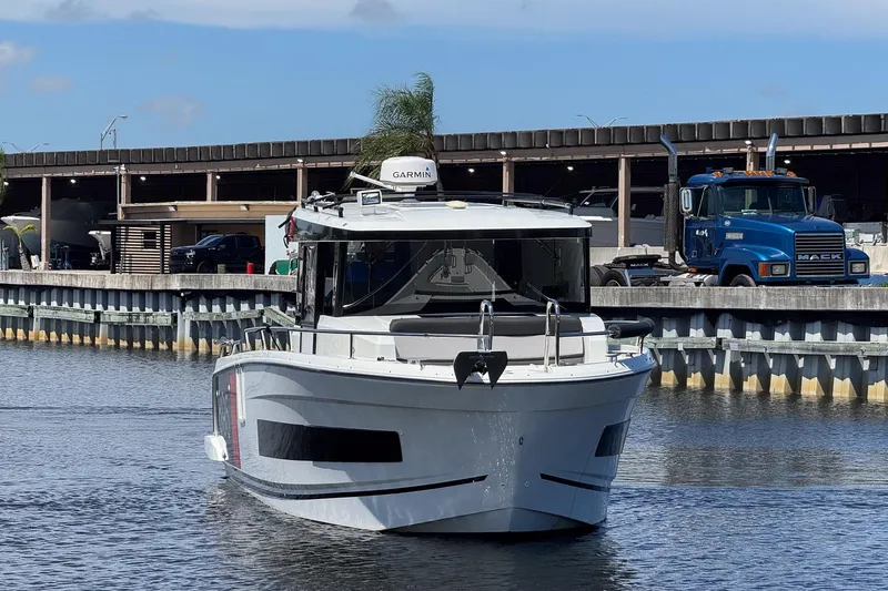  Yacht Photos Pics 2018 Jeanneau NC 895 boat docked near industrial area with truck in background.