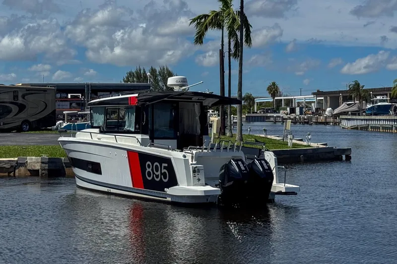  Yacht Photos Pics 2018 Jeanneau NC 895 boat docked in a marina under a blue sky.