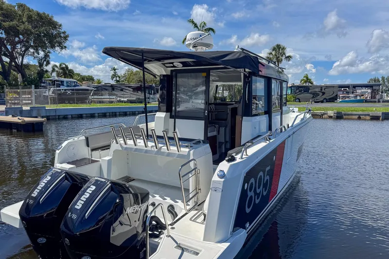  Yacht Photos Pics 2018 Jeanneau NC 895 boat docked, featuring twin Mercury V6 engines, under a clear blue sky.