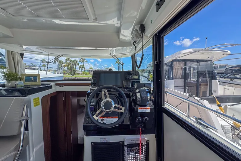  Yacht Photos Pics Interior view of 2018 Jeanneau NC 895 boat cockpit with steering wheel and navigation equipment.