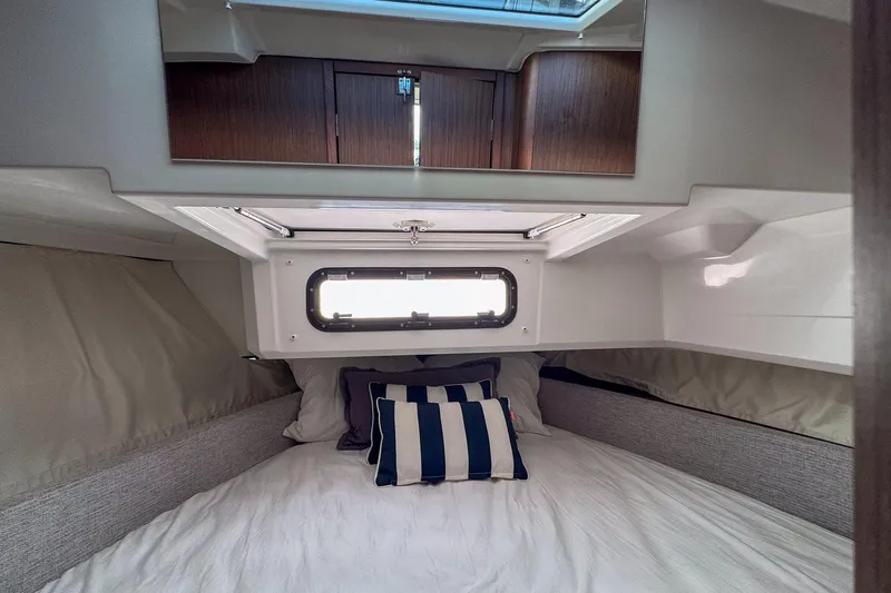  Yacht Photos Pics Cozy cabin interior of 2018 Jeanneau NC 895 with striped pillows and window.