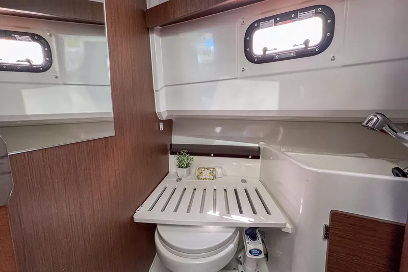  Yacht Photos Pics 2018 Jeanneau NC 895 boat bathroom with compact design and wooden accents.