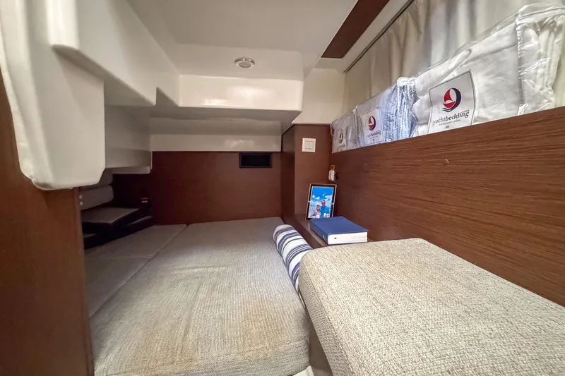  Yacht Photos Pics 2018 Jeanneau NC 895 cabin interior with cozy bedding and wooden accents.