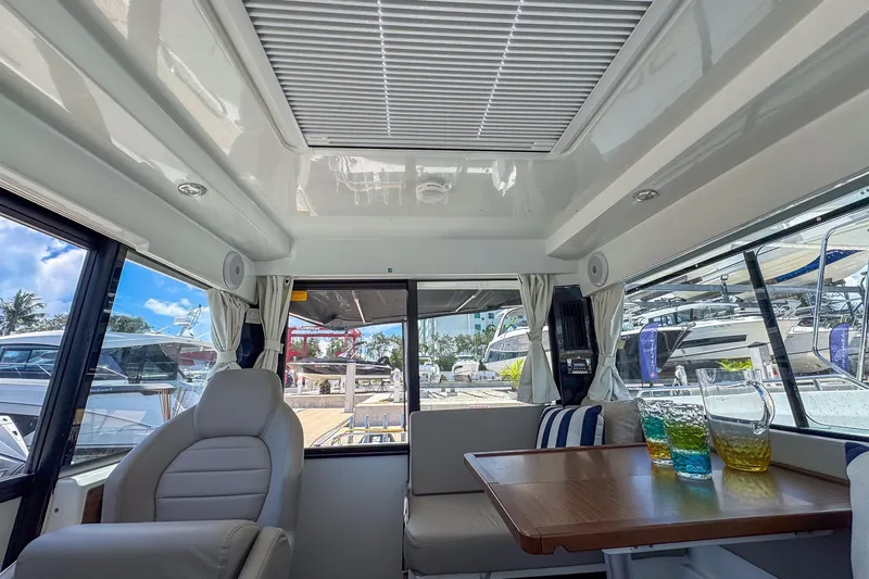  Yacht Photos Pics Interior of 2018 Jeanneau NC 895 boat with seating and table, featuring colorful drinks.