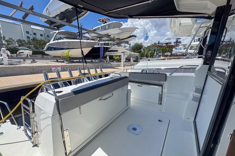  Yacht Photos Pics 2018 Jeanneau NC 895 boat deck with seating, docked at marina under clear sky.