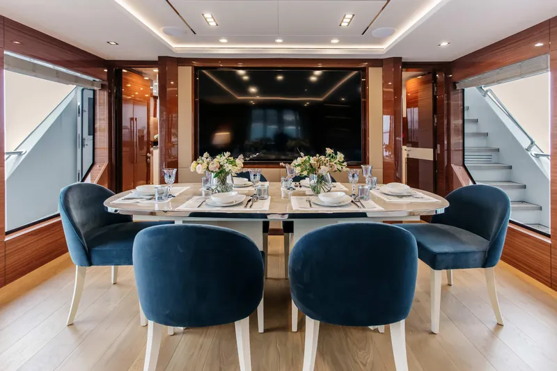 Papillon Yacht Photos Pics Luxurious dining area on 2022 Bering 92 yacht with elegant table setting and blue chairs.