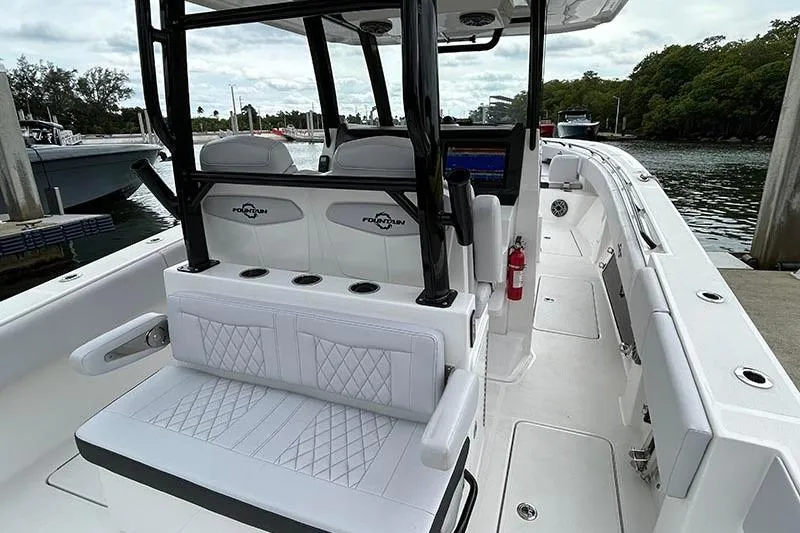  Yacht Photos Pics 2025 Fountain 38 Center Console boat interior with white seating and black accents at a marina.