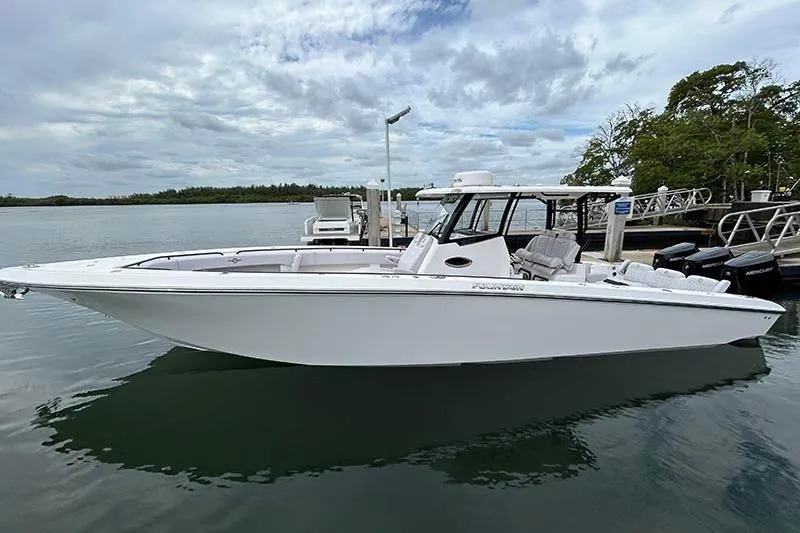  Yacht Photos Pics 2025 Fountain 38 Center Console boat docked on calm water under cloudy sky.