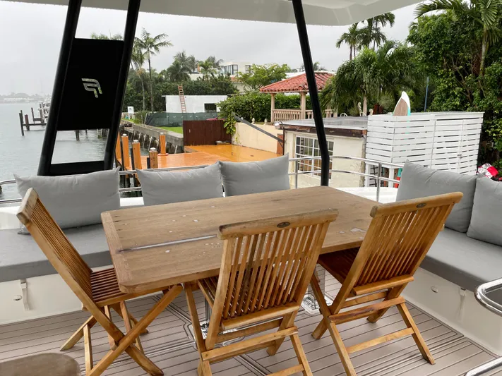 Fina Yacht Photos Pics Outdoor seating area on a 2020 Fountaine Pajot MY 44 yacht, featuring wooden table and chairs.
