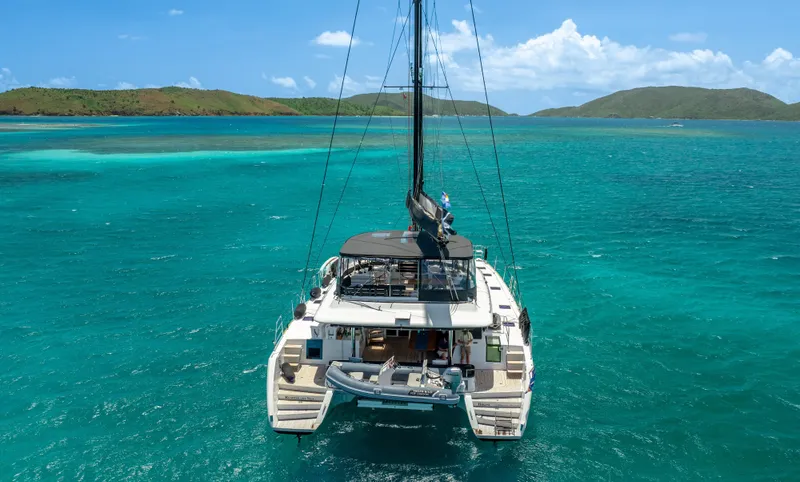 Respite At Sea Yacht Photos Pics Lagoon 560 catamaran sailing in turquoise waters, 2018 model, with scenic island backdrop.