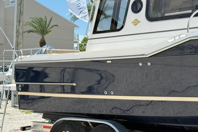  Yacht Photos Pics 2025 Ranger Tugs R-23 boat, navy blue hull, parked on a trailer, palm tree background.