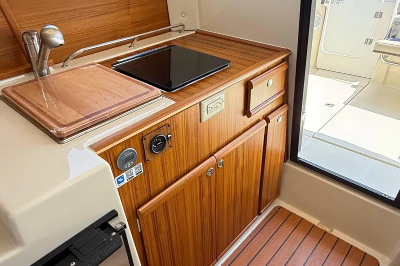  Yacht Photos Pics 2025 Ranger Tugs R-23 interior kitchen with wooden cabinetry and modern appliances.