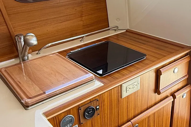  Yacht Photos Pics 2025 Ranger Tugs R-23 interior kitchen with wooden cabinetry and modern appliances.