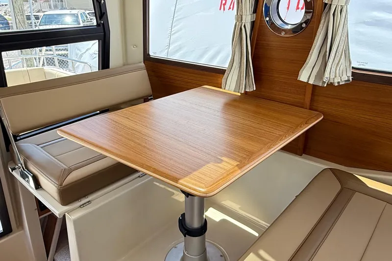 Yacht Photos Pics Interior of 2025 Ranger Tugs R-23, featuring a wooden table and cushioned seating.