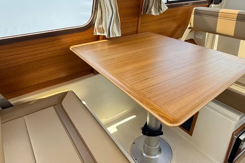  Yacht Photos Pics Interior of 2025 Ranger Tugs R-23, featuring a wooden table and cushioned seating.