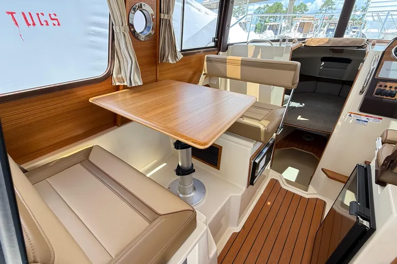  Yacht Photos Pics 2025 Ranger Tugs R-23 interior with wood table, beige seating, and nautical decor.