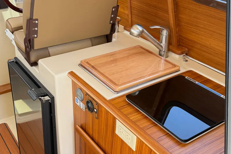  Yacht Photos Pics 2025 Ranger Tugs R-23 interior with kitchenette, featuring a sink, cutting board, and stove.