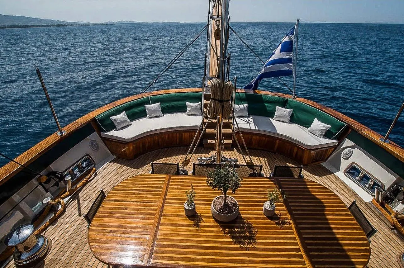 Luxurious yacht deck with wooden table, Greek flag, and ocean view, custom model 2004.