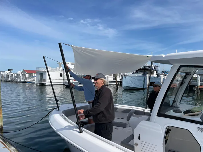 Ice Blue Yacht Photos Pics 2024 Everglades 285CC boat with sunshade, docked at marina, people adjusting canopy.