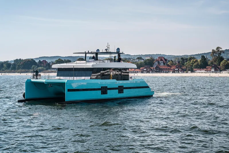 Rockstar 2.0 Yacht Photos Pics 2018 Sunreef 68 Supreme catamaran sailing near a scenic coastal town.