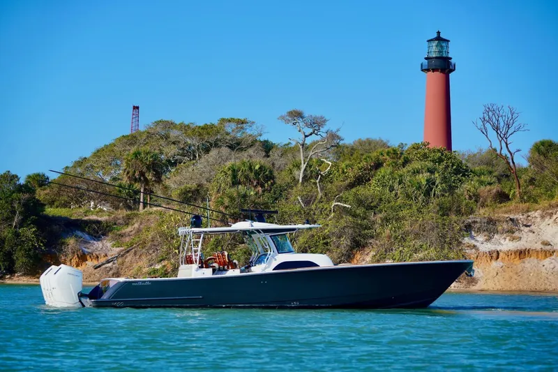 Rhyde Yacht Photos Pics 2021 Valhalla Boatworks V46 cruising near a lighthouse with lush greenery.