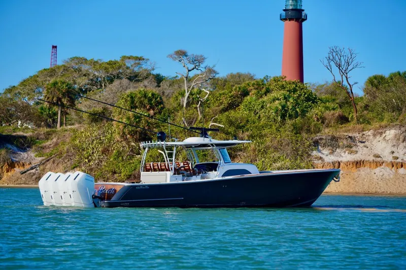 Rhyde Yacht Photos Pics 2021 Valhalla Boatworks V46 cruising near a lighthouse, surrounded by lush greenery.