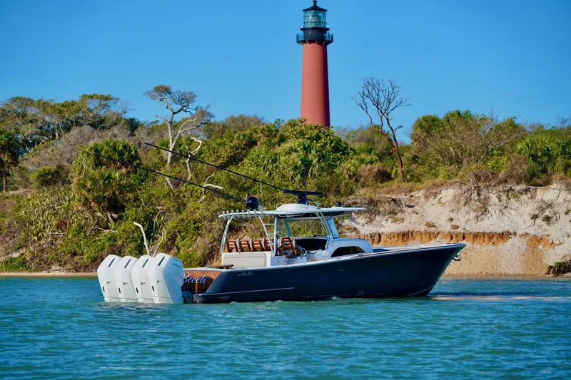 Rhyde Yacht Photos Pics 2021 Valhalla Boatworks V46 cruising near a lighthouse with lush greenery in the background.