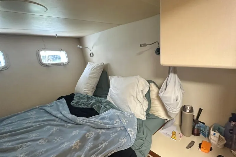 Adventurer Yacht Photos Pics Cozy cabin bedroom in 1985 Burger 94 yacht with unmade bed and porthole windows.