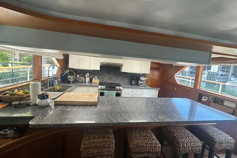 Adventurer Yacht Photos Pics Luxurious yacht kitchen interior with marble countertops, wicker stools, and modern appliances on a 1985 Burger 94.