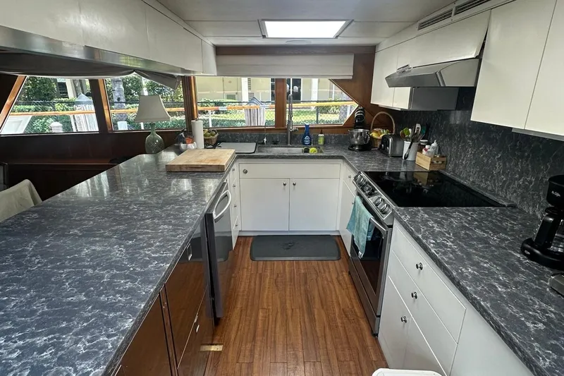 Adventurer Yacht Photos Pics Modern kitchen interior on a 1985 Burger 94 yacht, featuring sleek countertops and wooden flooring.