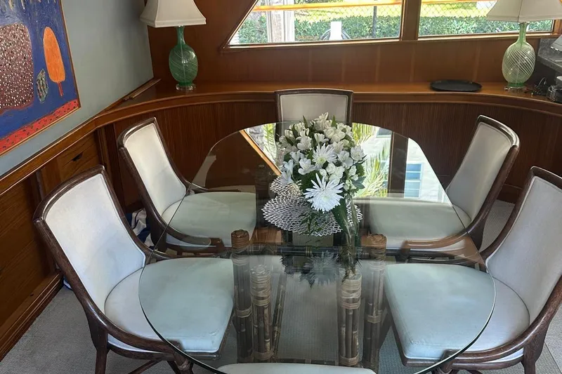 Adventurer Yacht Photos Pics Elegant dining area on 1985 Burger model 94 yacht with glass table and floral centerpiece.